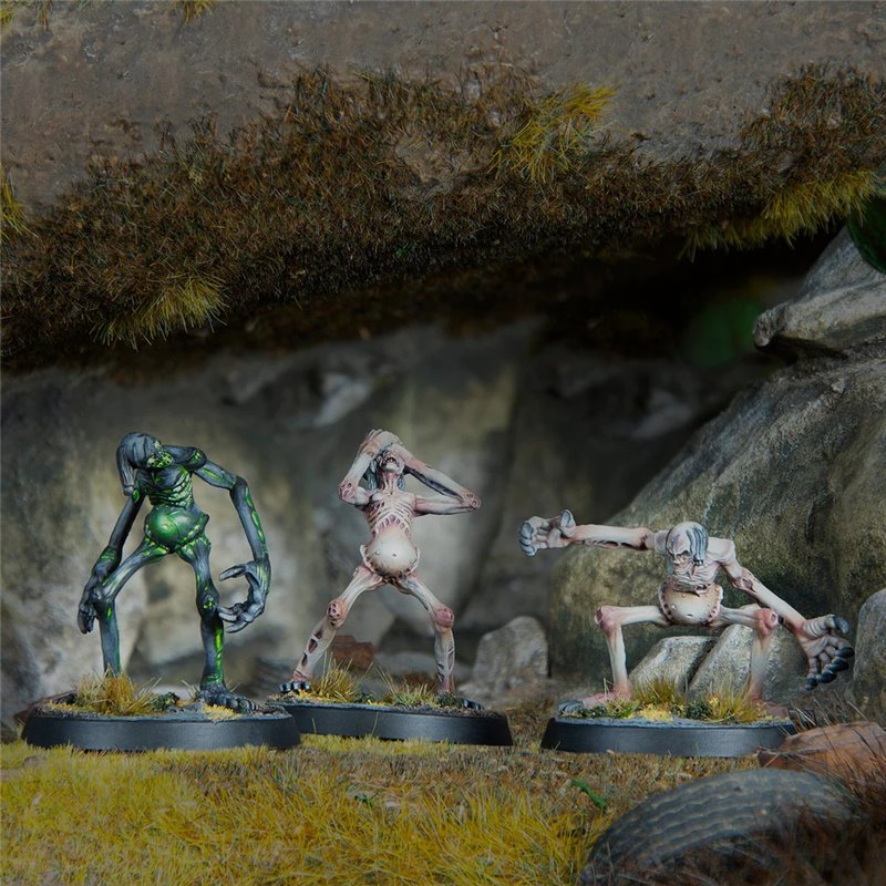 Three painted miniatures of gaunt, monstrous creatures: one green, one pale with hands over head, and one pale lunging, on rocky terrain.