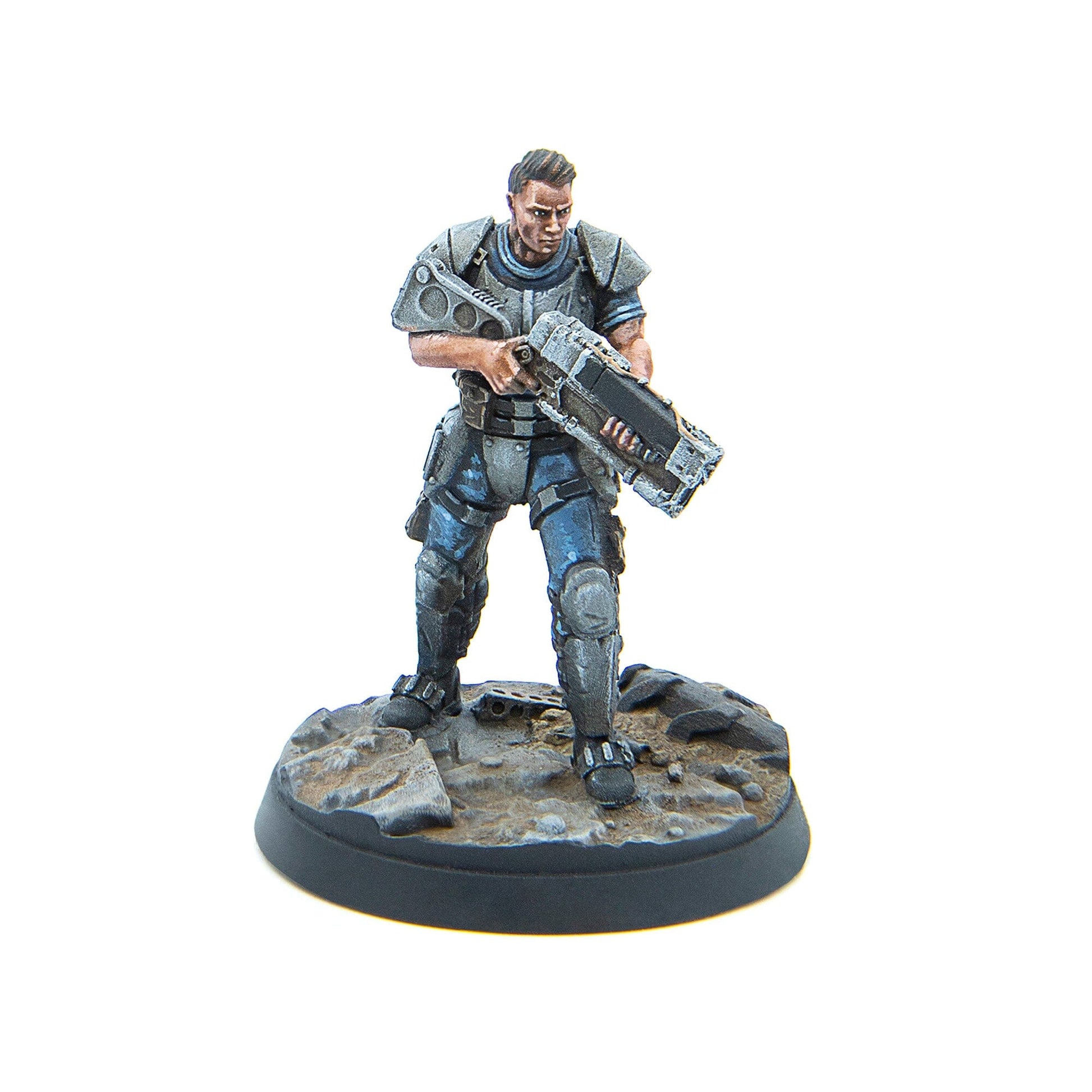 A male miniature soldier in grey and blue armor stands on a rocky base, holding a large futuristic rifle