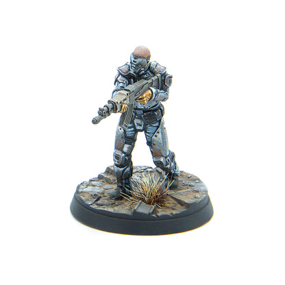 A painted miniature of a futuristic soldier in grey battle armor, holding a rifle, standing on a rocky, debris-strewn base