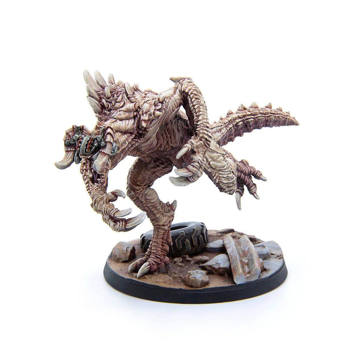 A highly detailed miniature of a beige and brown monster with spikes and claws, standing on a round base with rocks and a tire