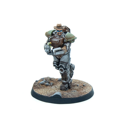A miniature of a character in Fallout-style power armor, wearing a cowboy hat and sunglasses, running while holding a small gun