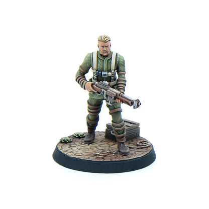 A wargaming miniature: a soldier in green uniform with blonde hair and beard, holding a sci-fi rifle, on a textured base