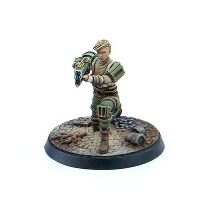 Painted miniature of a blonde woman in green/beige armor, kneeling and aiming a futuristic weapon on a textured base
