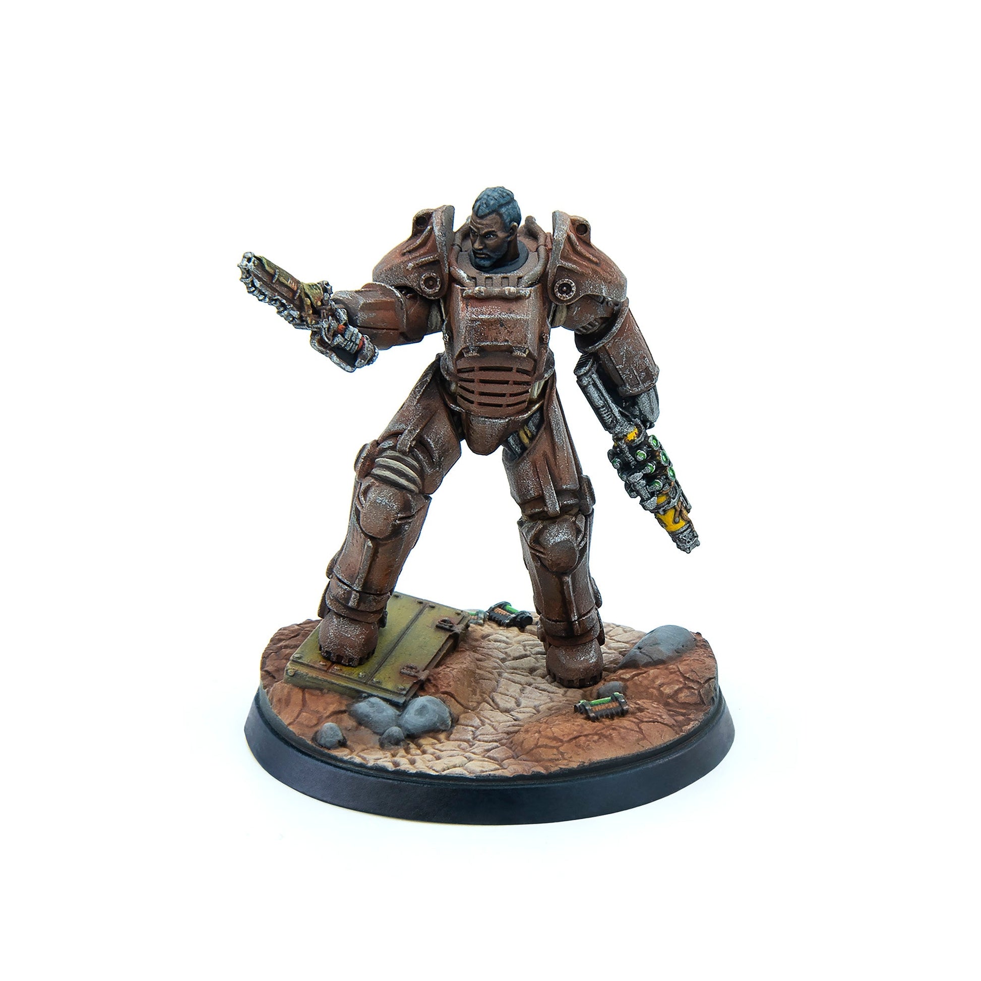 A miniature of a man in rusty Fallout power armor, holding a chainsaw weapon and energy rifle on a debris-strewn base