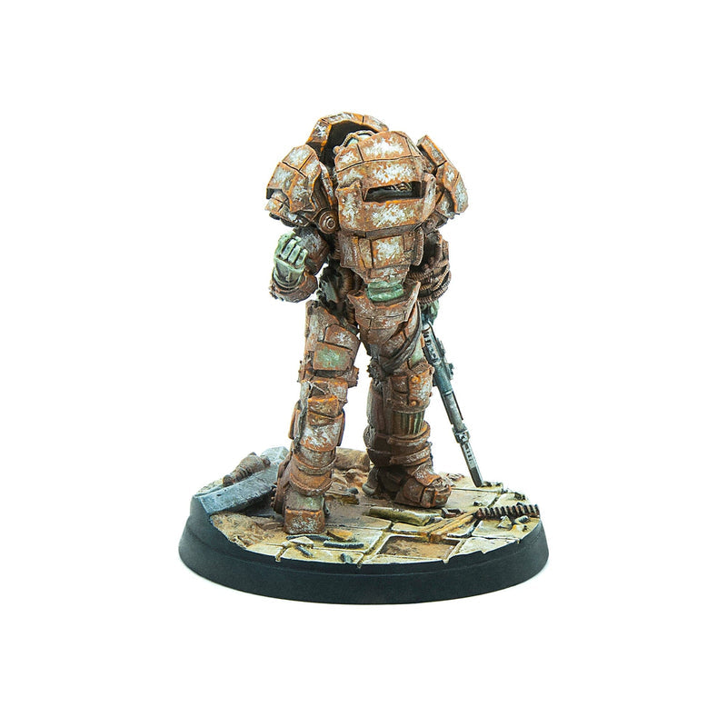 A tabletop miniature of a rusty, heavily armored figure standing with a rifle on a ruined base