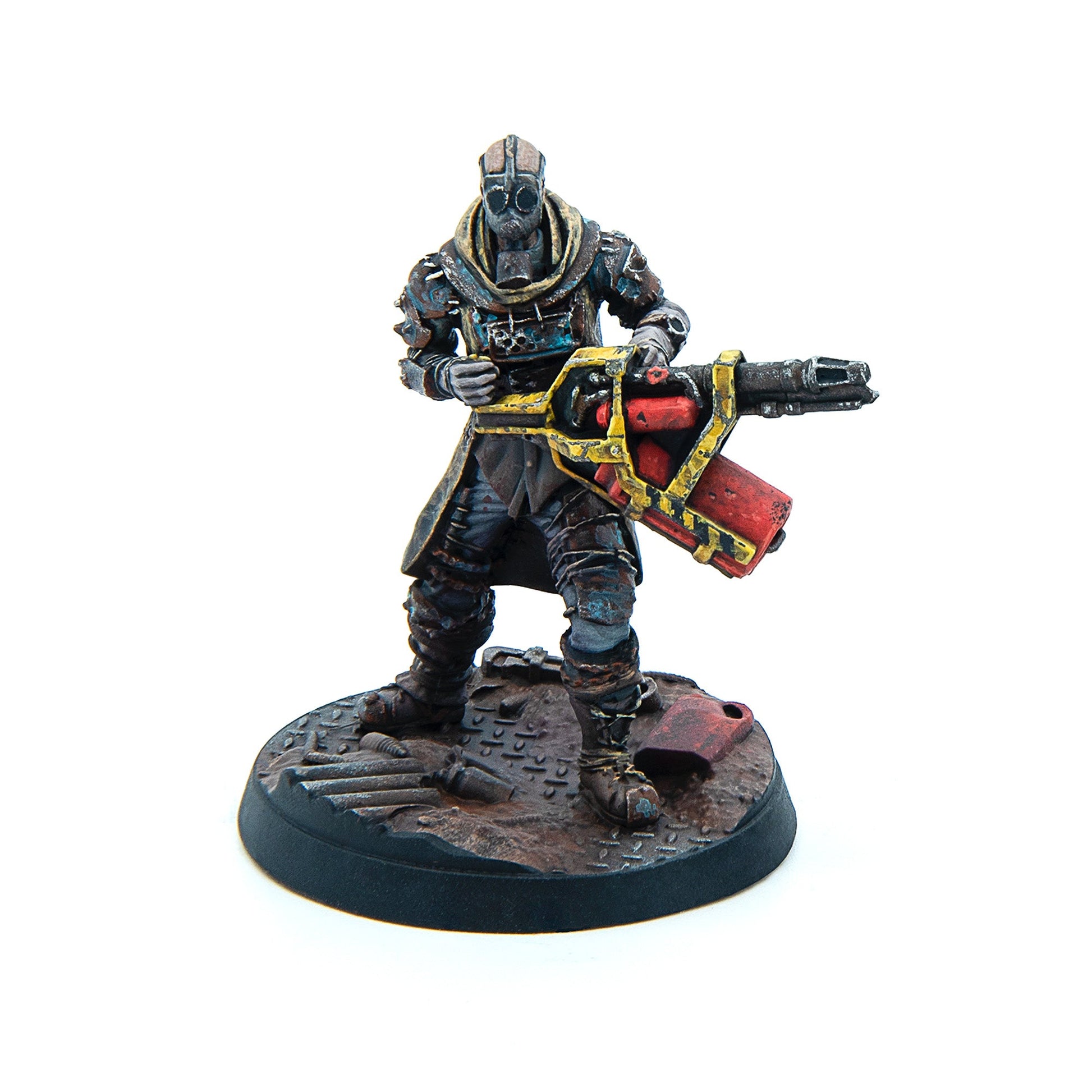 A post-apocalyptic miniature figure in a gas mask and goggles, holding a large red & yellow sci-fi weapon on a rusty industrial base