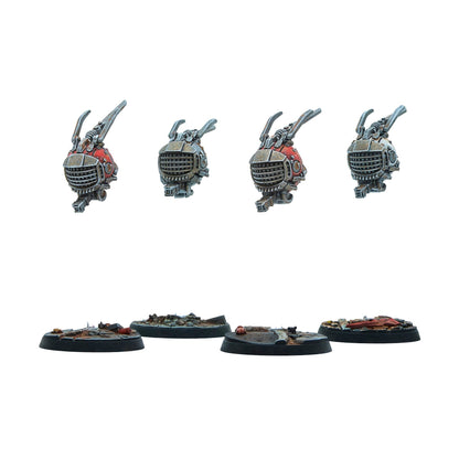 Four miniature robot components (two red, two grey) with claw arms, displayed above four rubble-covered bases