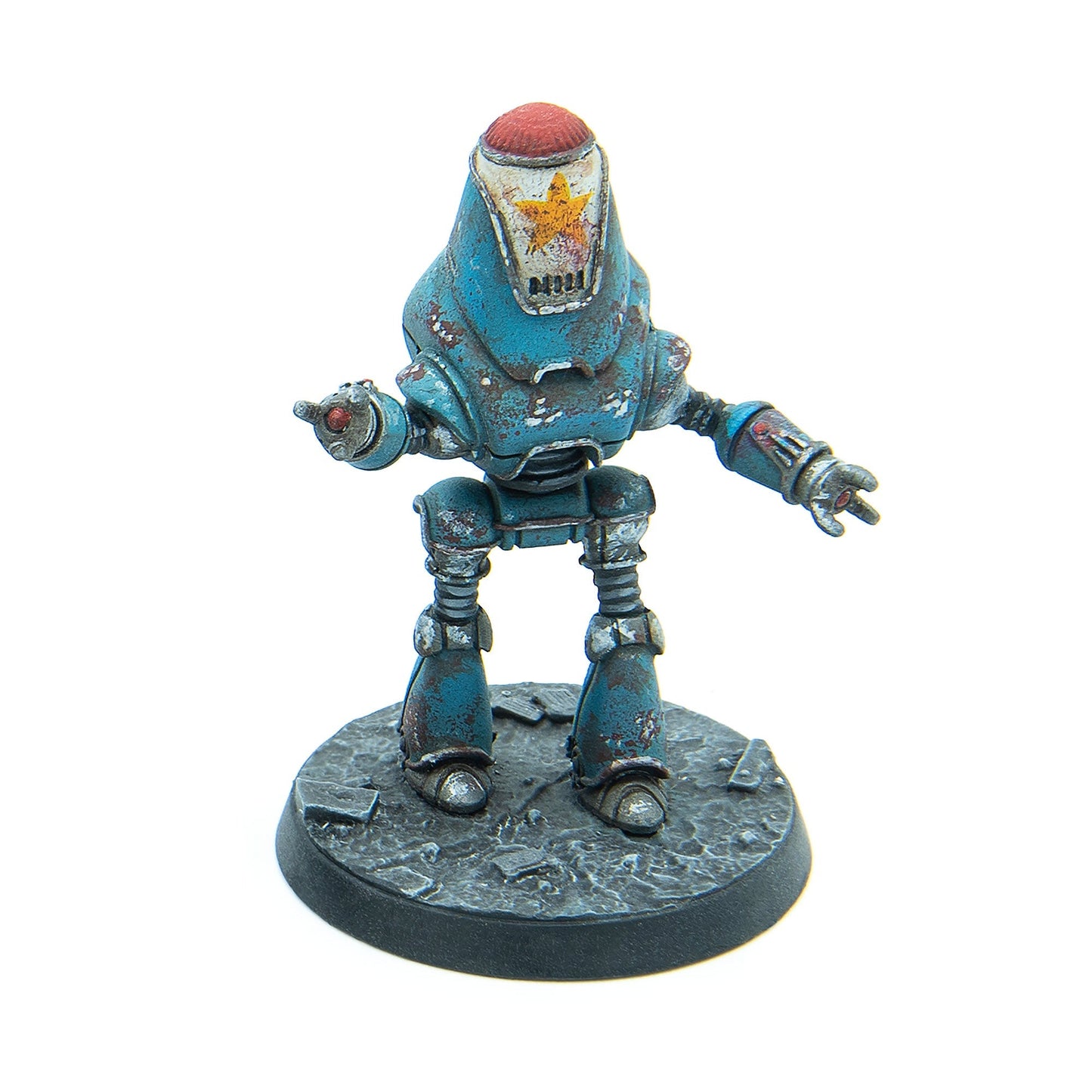 A retro-futuristic blue robot miniature, heavily rusted, with a red dome and a yellow star on its face, standing on a textured base