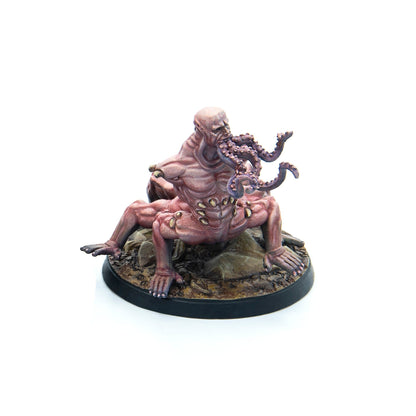 A miniature figure of a grotesque pale creature with a bald head, four limbs, and purple tentacles around its mouth and chest on a rocky base