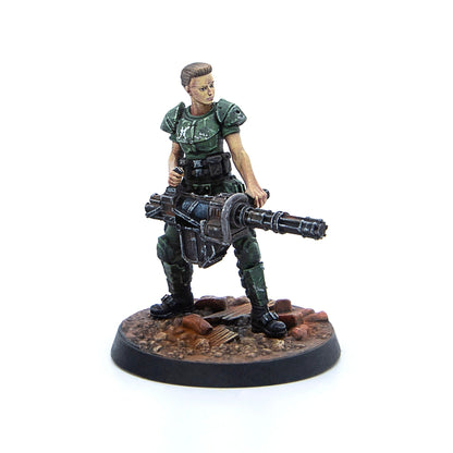 Painted female miniature in green armor holds a large minigun on a rubble base