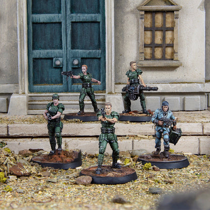 Five armed miniature soldiers in green and blue uniforms stand on a debris base with a building backdrop
