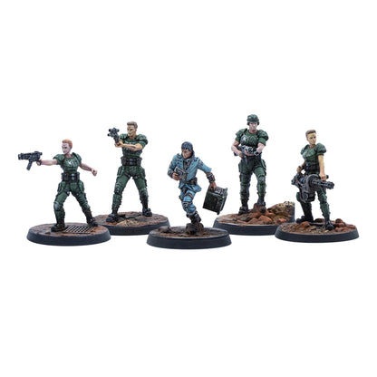 Five sci-fi miniature figures: four armed marines in green armor, and one character in blue running with a device and crate