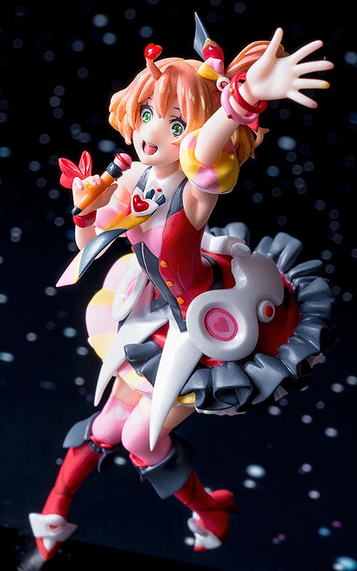 Orange-haired anime figure in red and pink stage outfit singing into a microphone