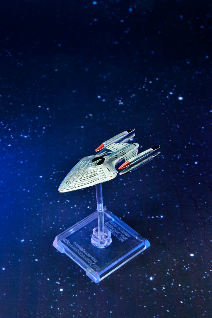 Silver sci-fi ship model on a clear stand, against a deep blue starry space background