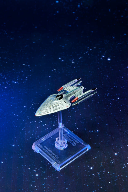 Silver sci-fi ship model on a clear stand, against a deep blue starry space background