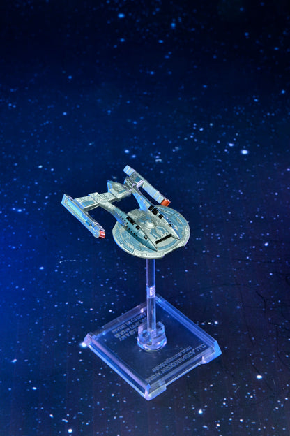 A metallic blue and silver sci-fi spaceship model, with a central disc and two large nacelles, on a stand against a starfield