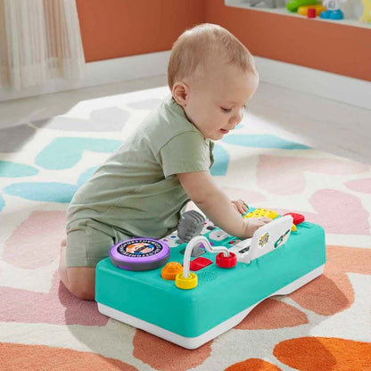 Baby kneels on a colorful rug -  pressing buttons on a teal interactive learning toy
