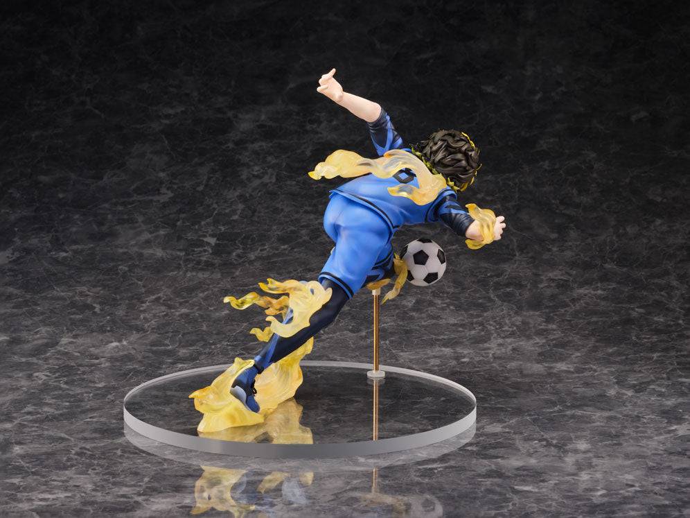 Anime action figure of a soccer player in a blue and yellow uniform kicking a ball on a clear circular base