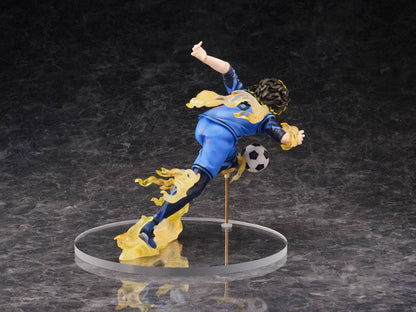 Anime action figure of a soccer player in a blue and yellow uniform kicking a ball on a clear circular base