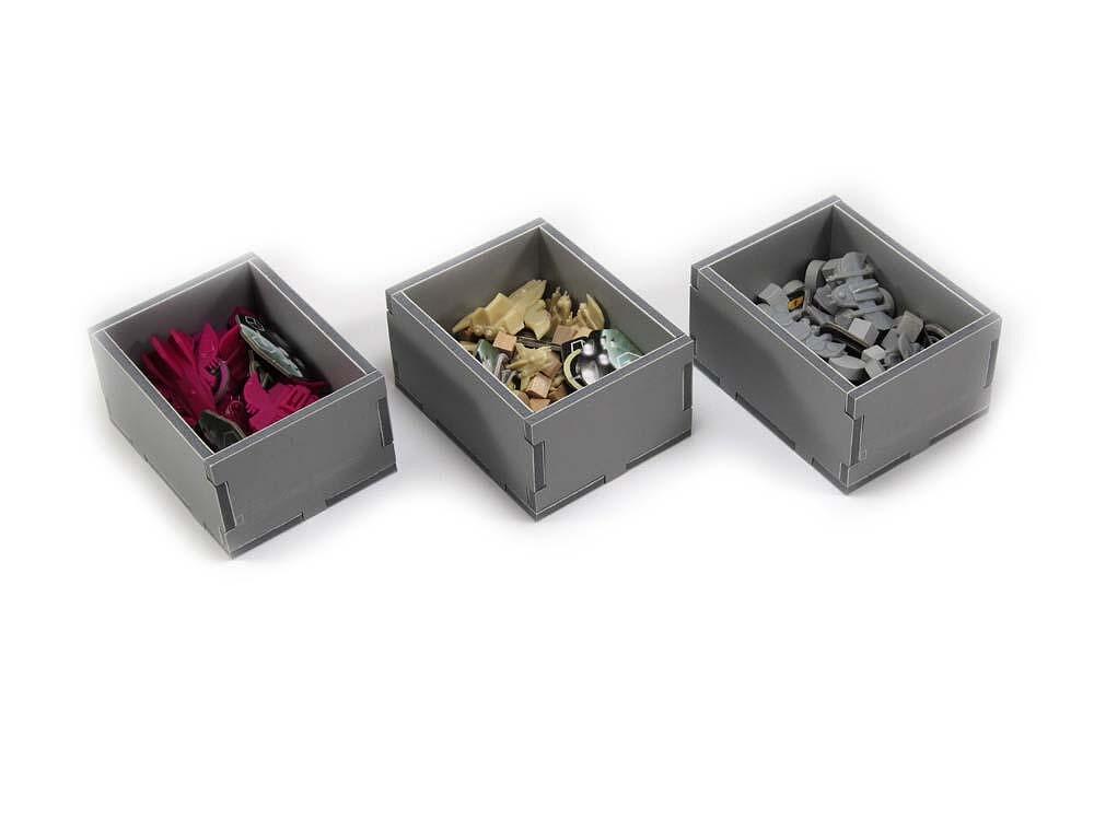Three gray organizer trays filled with various small board game pieces