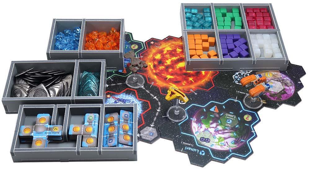 Overhead view of a sci-fi board game setup: a hexagonal star map with spaceships, planets, and trays of colorful components