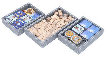 Three game inserts filled with board game tokens and resources