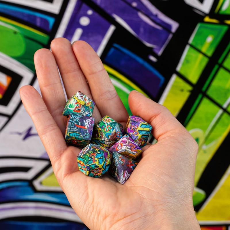 A hand cups multiple colorful, graffiti-patterned dice against a vibrant, blurry graffiti art background