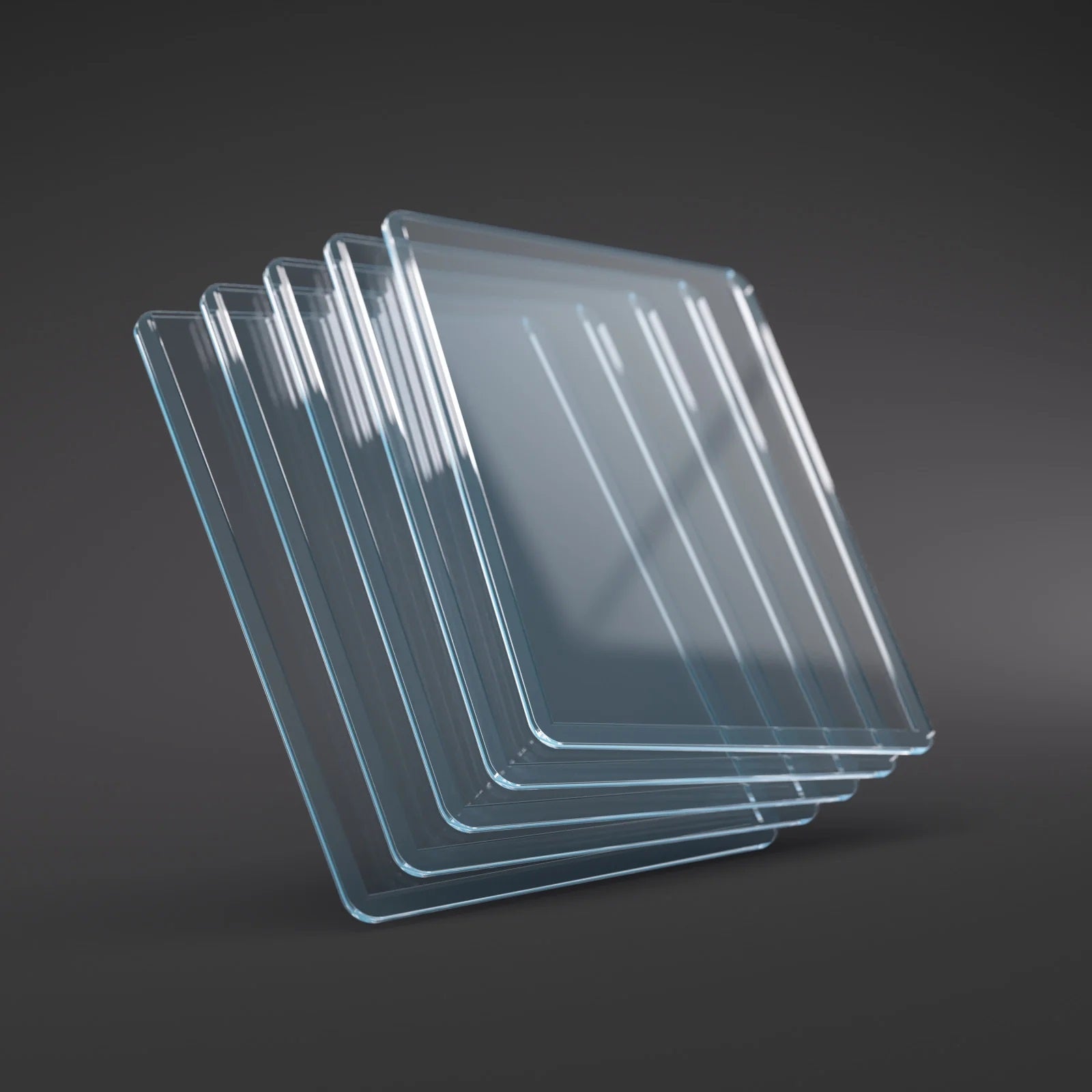Fanned stack of transparent square glass sheets with rounded corners on a dark grey surface