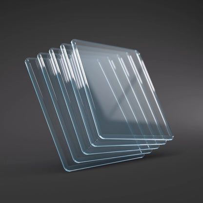 Fanned stack of transparent square glass sheets with rounded corners on a dark grey surface