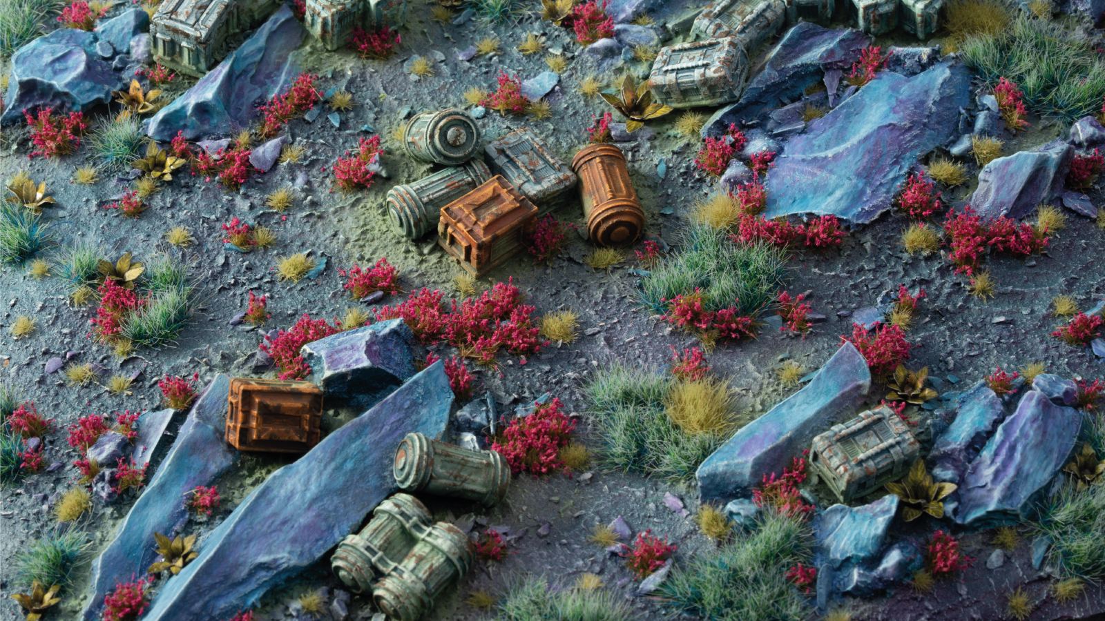 Detailed miniature terrain featuring scattered crates, blue rocks, and patches of bright red and green overgrown plants