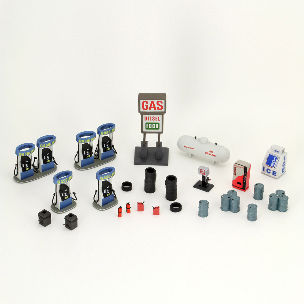 A collection of miniature gas station elements: gas pumps, a 'GAS DIESEL FOOD' sign, propane tank, and various accessories