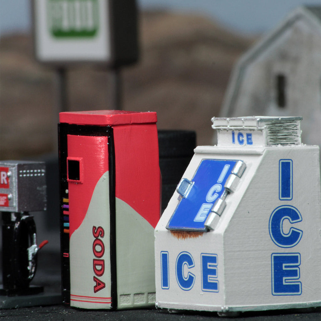 A miniature red soda machine and a white ice machine, labeled "SODA" and "ICE", stand side-by-side
