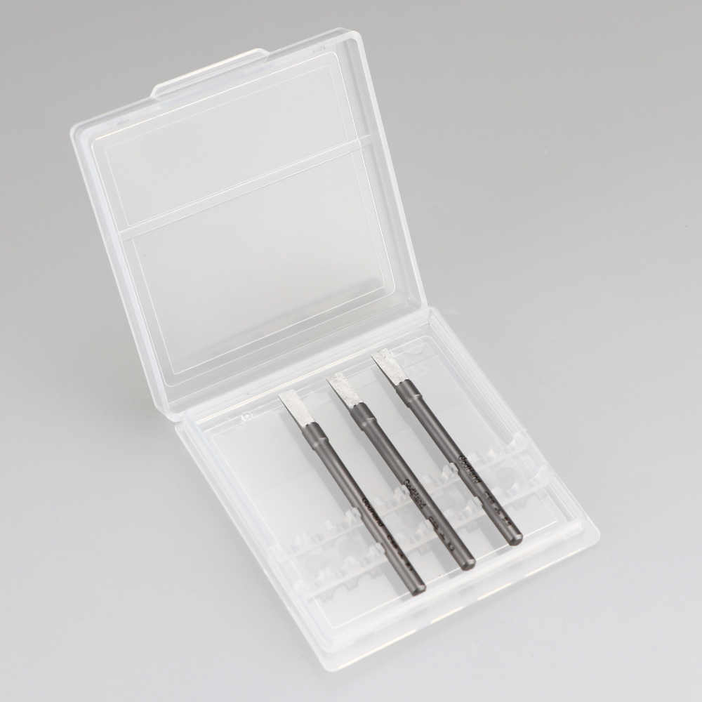 Three dark chisel-tipped tools in an open clear plastic storage case