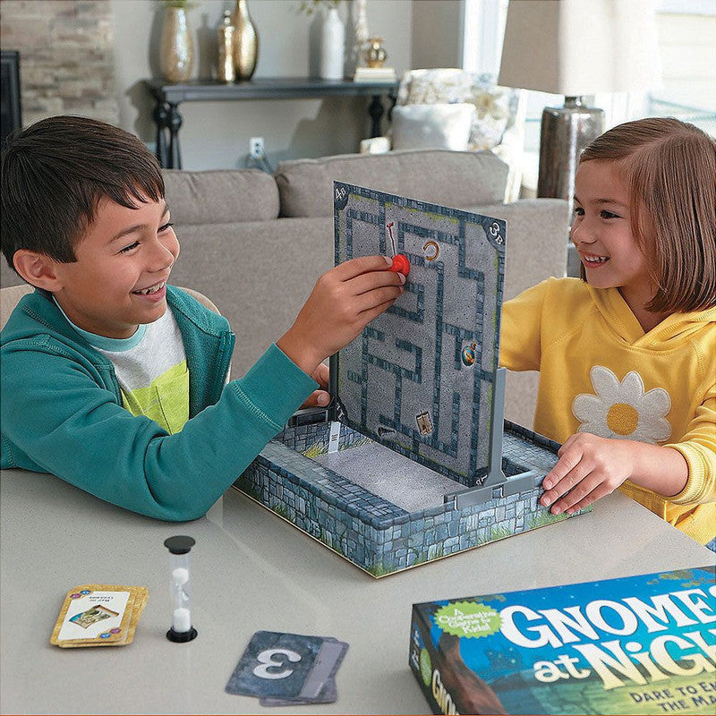 Two children playing Gnomes at Night cooperative strategy board game moving game pieces on the maze board with cards and hourglass timer