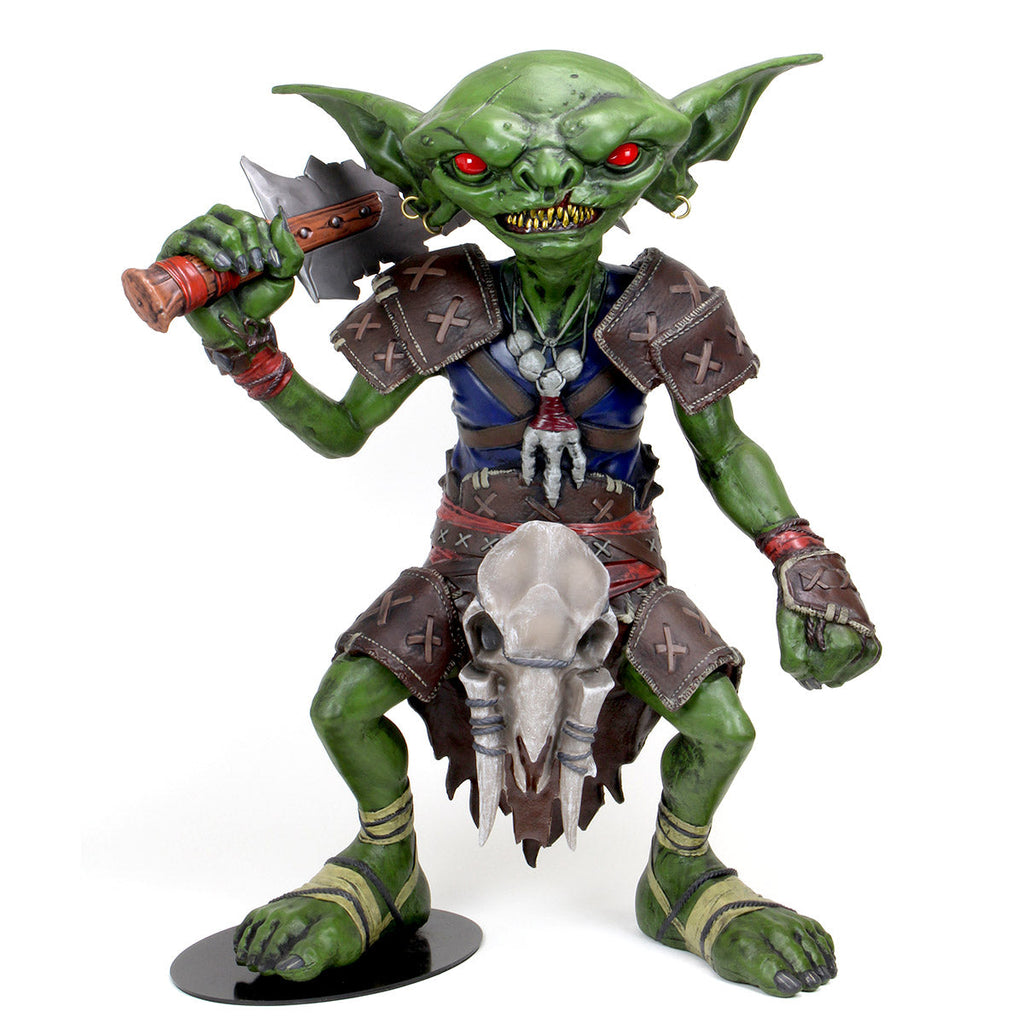 A menacing green goblin statue with red eyes, sharp teeth, holding an axe. Wears leather armor & skull decoration