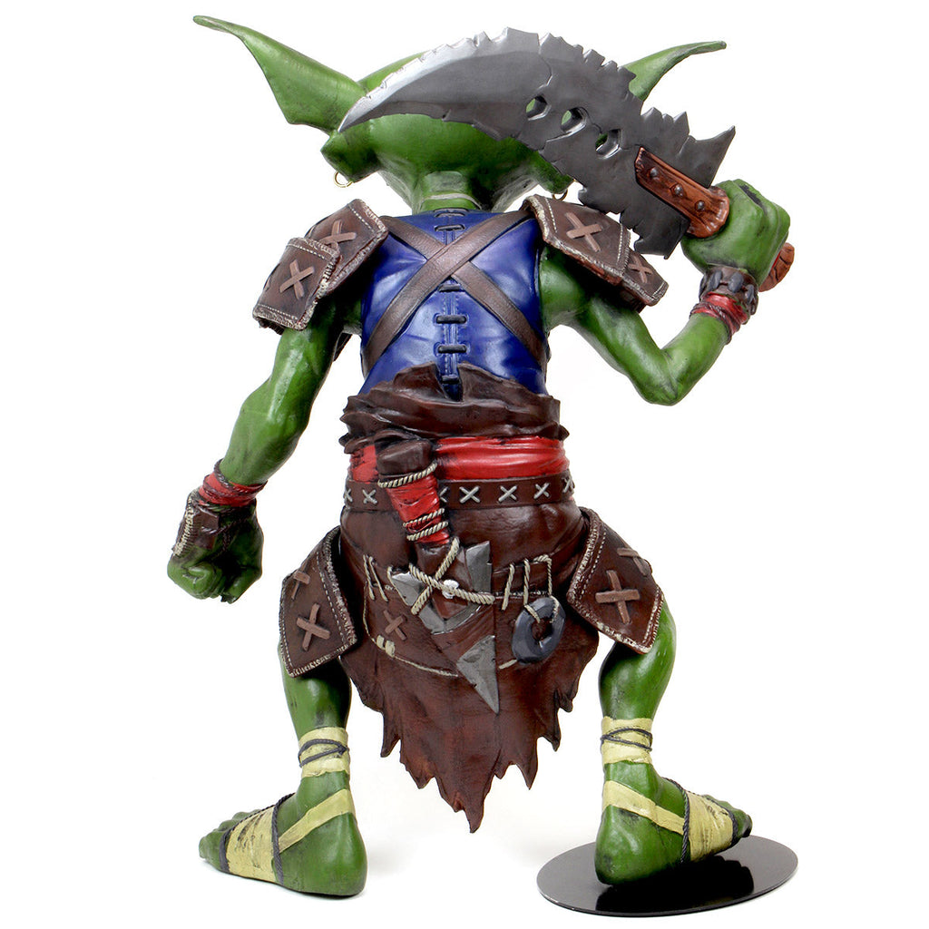 Green goblin warrior figure viewed from behind, wearing armor and a blue tunic, holding a jagged cleaver over its right shoulder