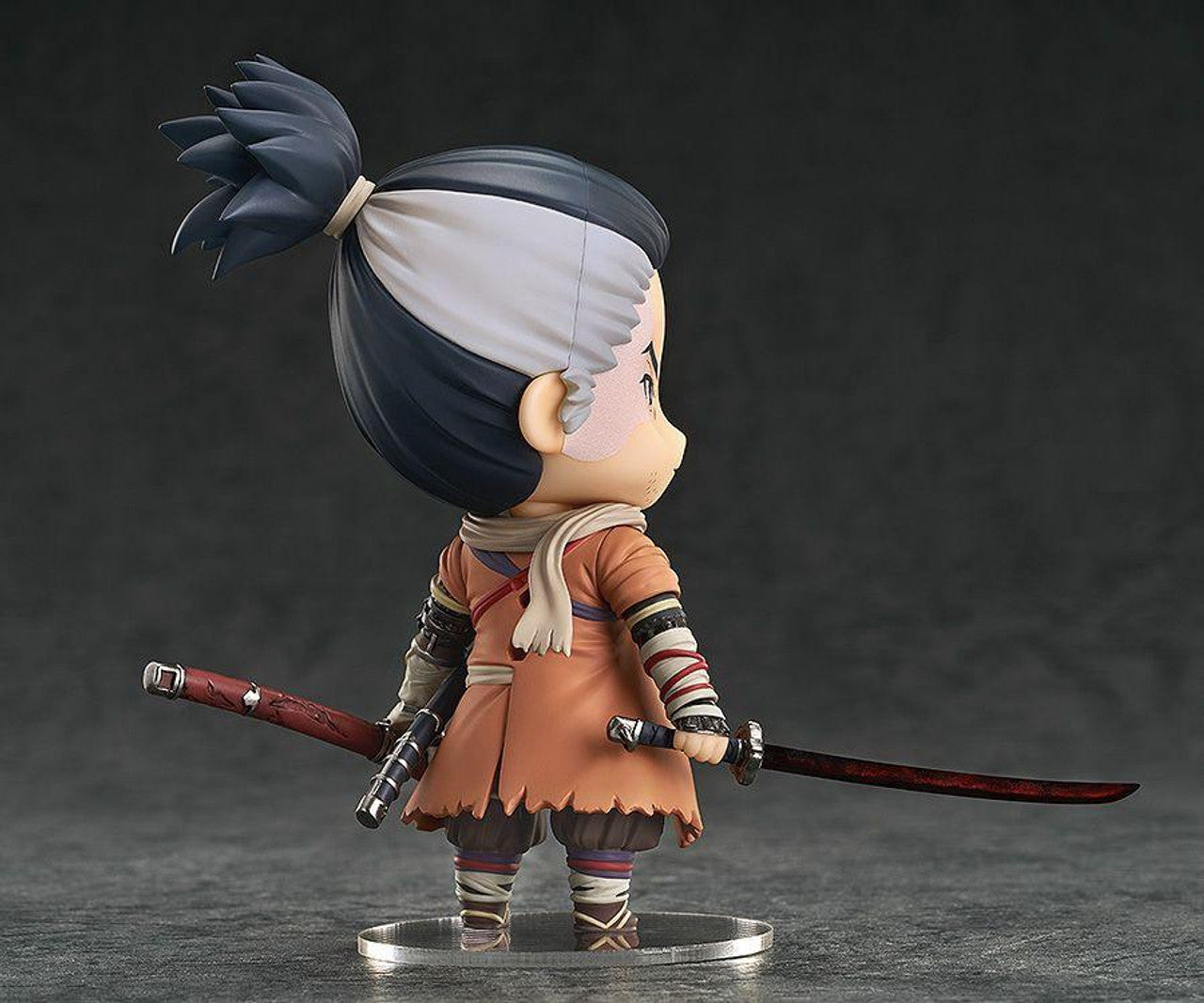 Sekiro Shadows Die Twice Nendoroid figure with hair tied back wearing orange coat and holding two swords