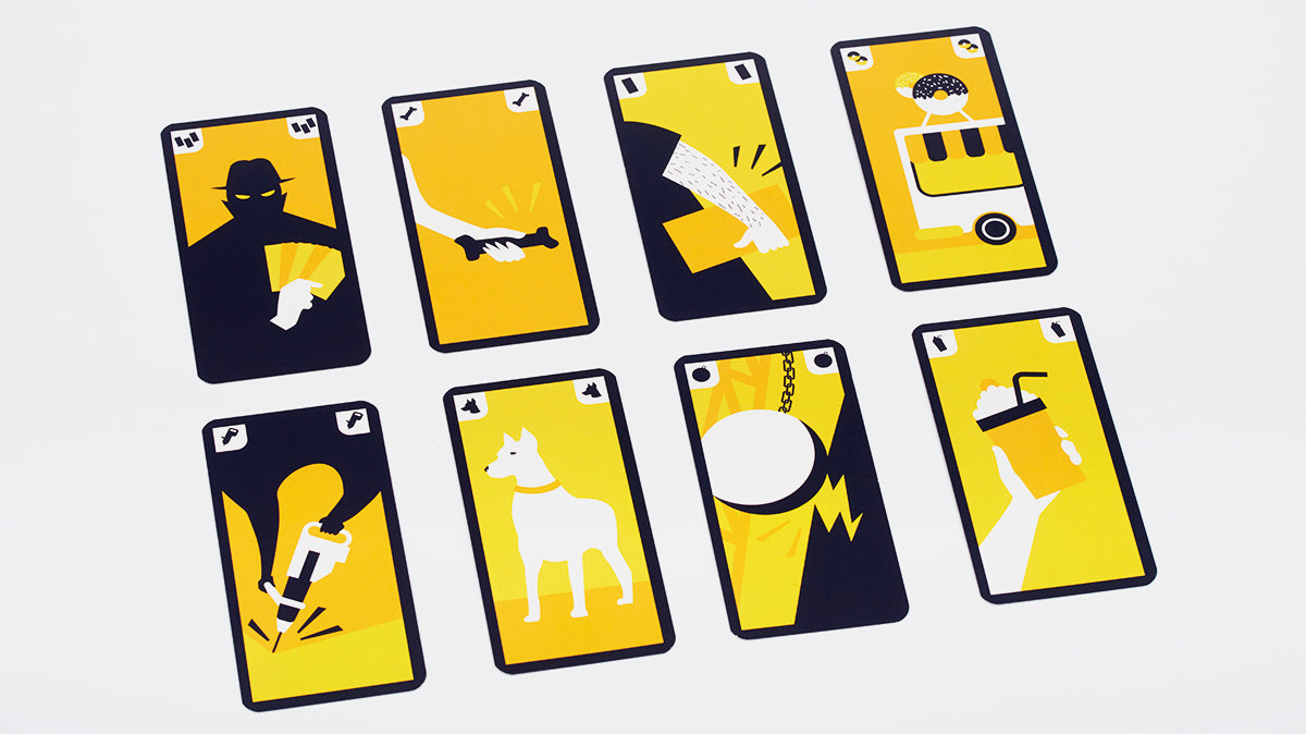 Eight yellow and dark blue game cards with illustrated graphics laid out on a white surface
