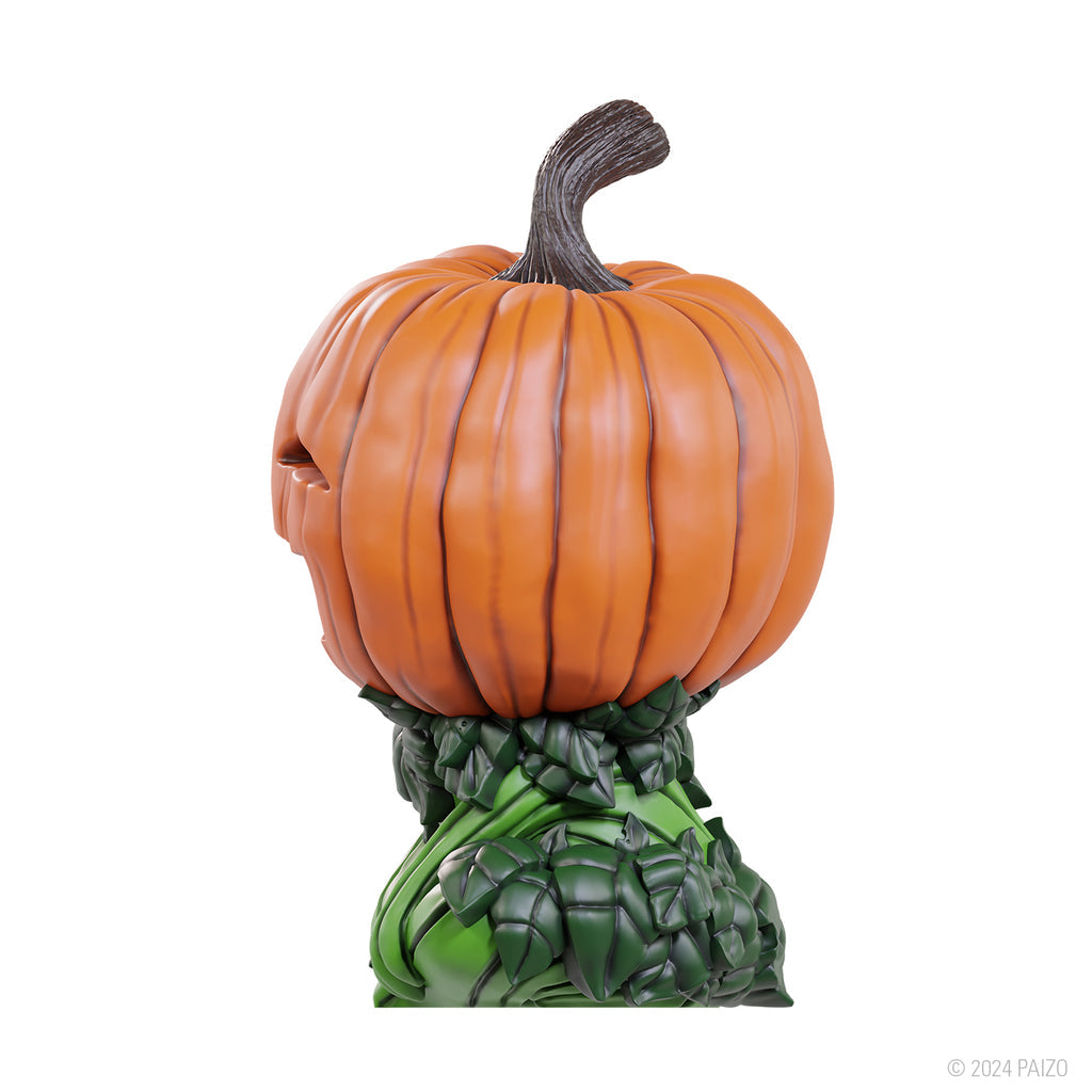 Orange gourd leshy figure with carved eyes and green leafy body, side view