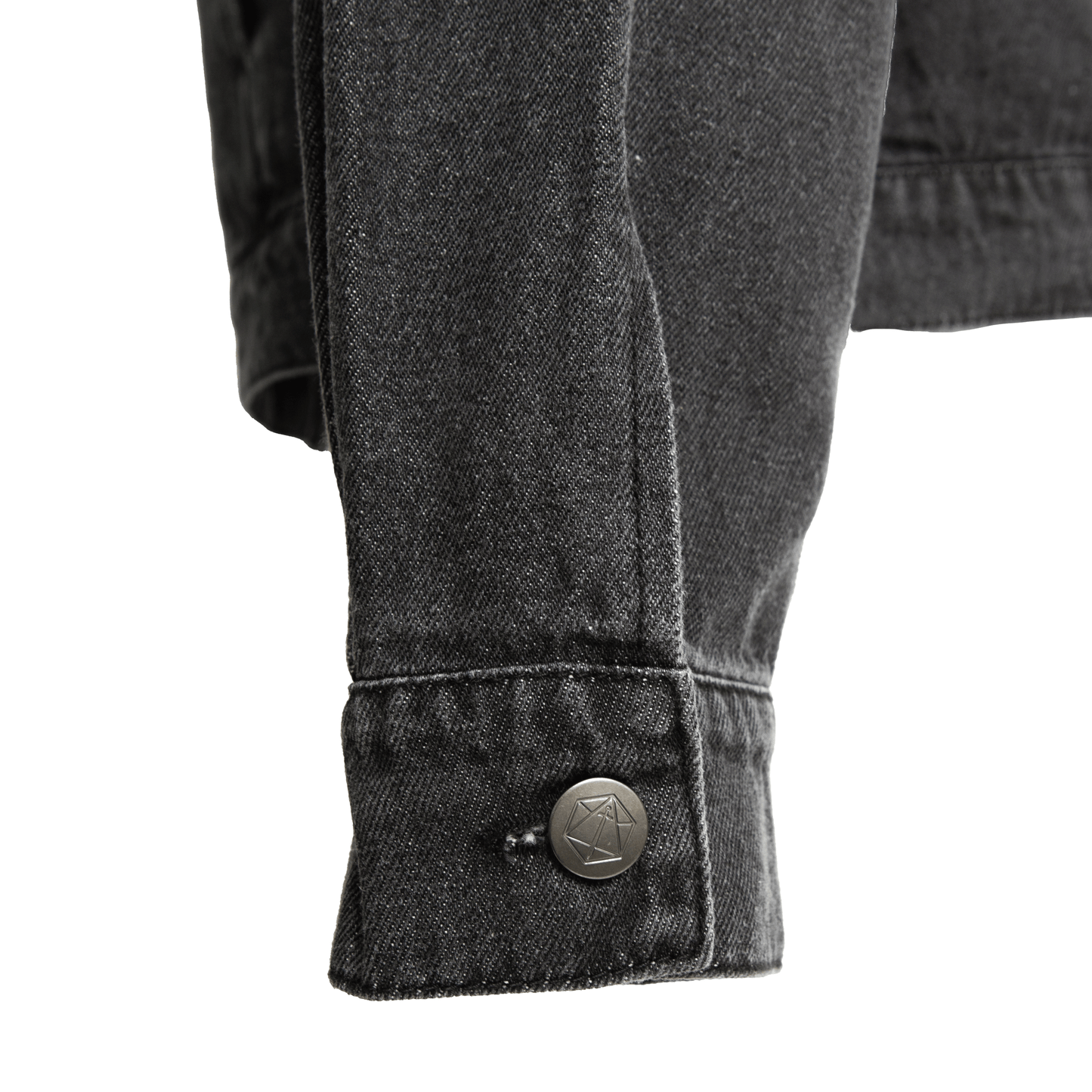 Close-up of a dark denim jacket cuff with a geometric button