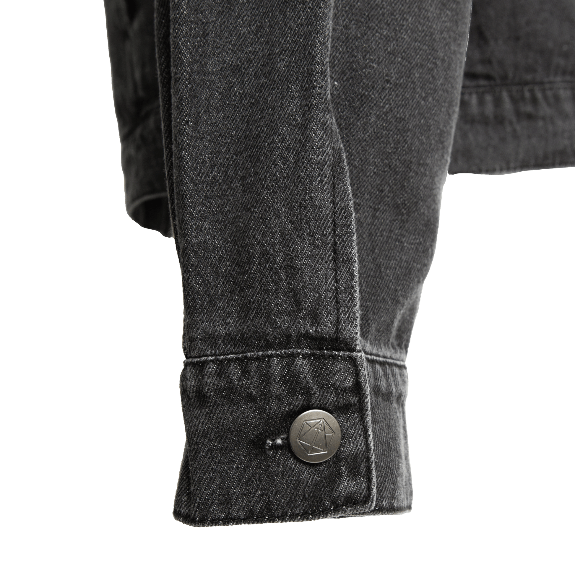 Close-up of a dark denim jacket cuff with a geometric button