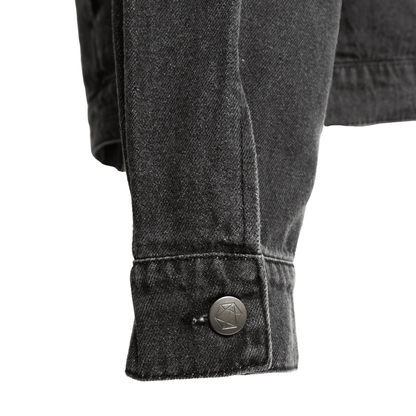 Close-up of a dark denim jacket cuff with a geometric button