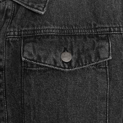 Dark grey denim jacket pocket with a metallic button showing a sword in a hexagon