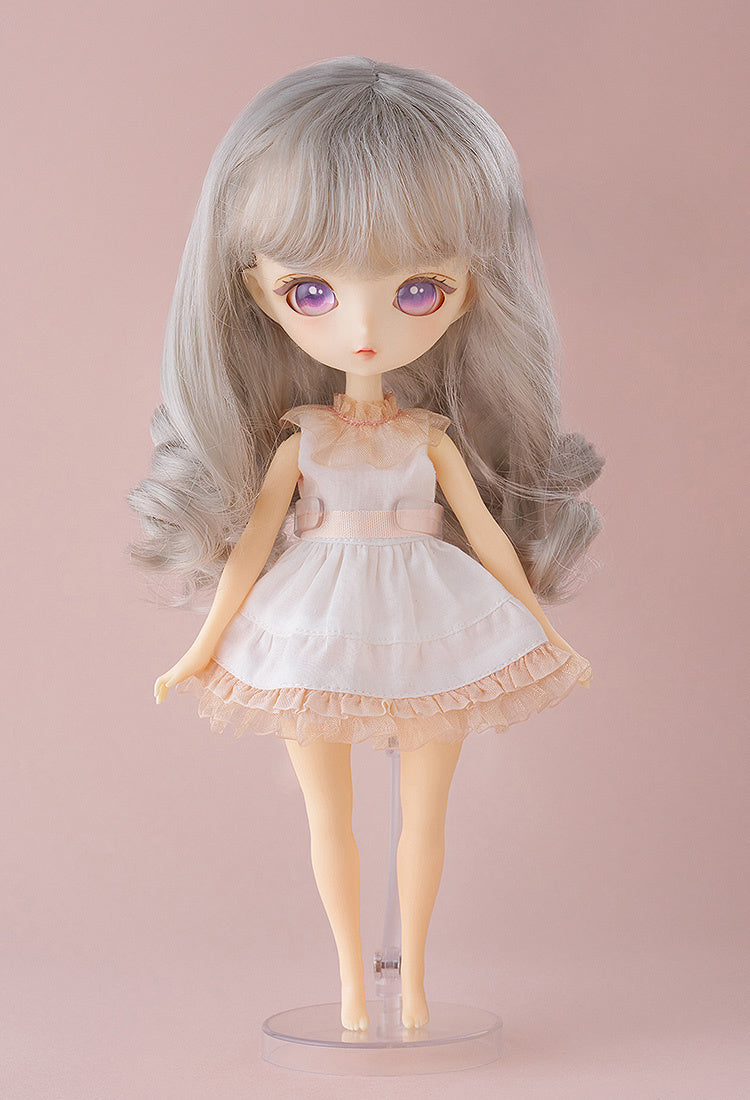 Mellow doll standing in pink dress with hands behind her back