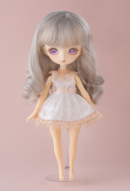 Mellow doll standing in pink dress with hands behind her back