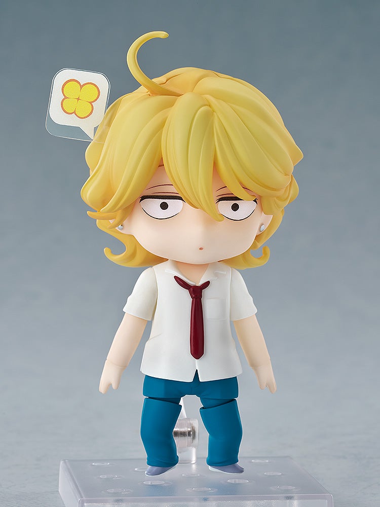 Blond Nendoroid figure wearing a white shirt, red tie, and blue pants, with a startled expression and a speech bubble with yellow clovers