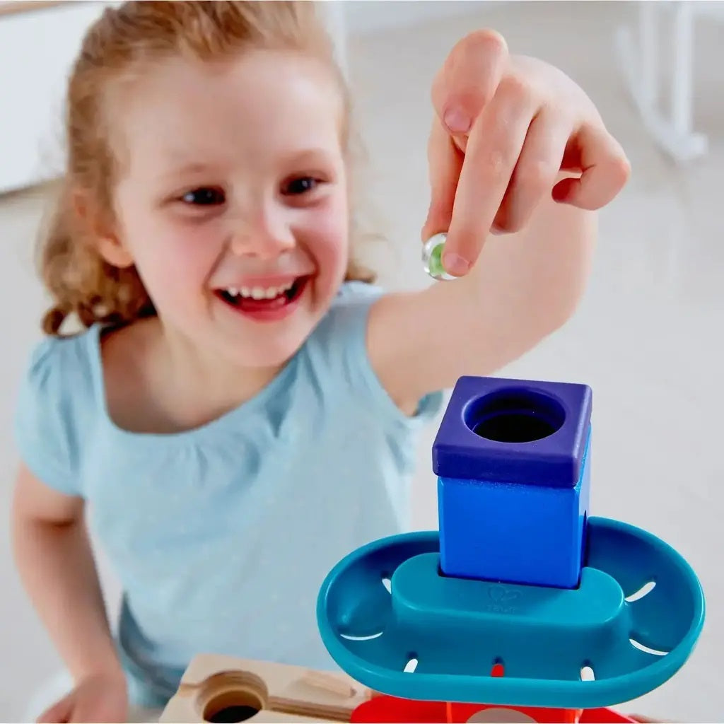Happy girl dropping a marble into a colorful stacking toy