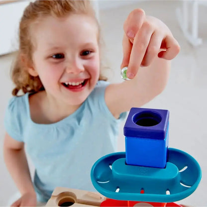 Happy girl dropping a marble into a colorful stacking toy
