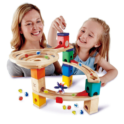 Smiling mother and daughter playing with a colorful wooden marble run