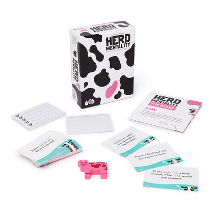 The party game Herd Mentality, featuring the cow-spotted box, question cards, rule book, and a pink wooden cow token